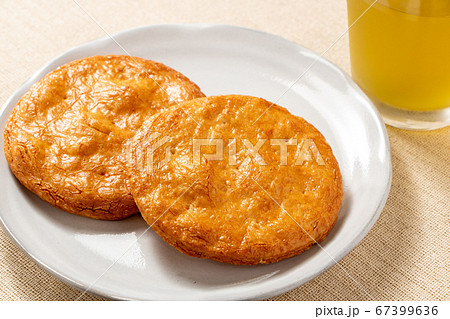 皿におかれたせんべい2枚。写真奥には冷たいお茶の入ったグラス。 皿におかれたせんべい2枚。写真奥には冷たいお茶の入ったグラス。 67399636