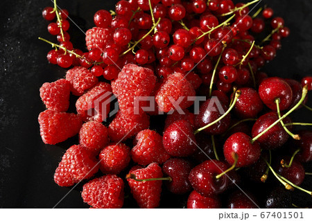 delicious and juicy red raspberries and cherries on a black table 67401501