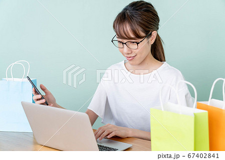 スマホとパソコンでオンラインショッピングをする若い女性 スマホとパソコンでオンラインショッピングをする若い女性 67402841
