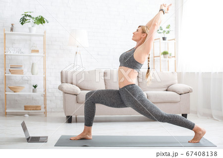 Fitness at home online. Woman in sportswear on sports mat with laptop in living room 67408138