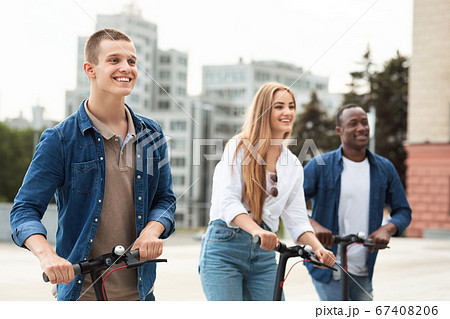 Friends riding motorized kick scooters in the city 67408206