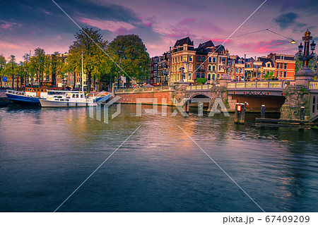 Dutch water canals with moored boats at sunset, Amsterdam, Netherlands  67409209