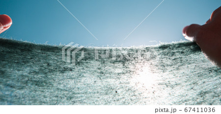 female hands hold woolen fabric against the sky, small fibers close-up 67411036