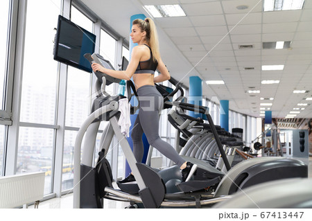 Young woman working out on orbi track at gym exercising Young woman working out on orbi track at gym exercising 67413447