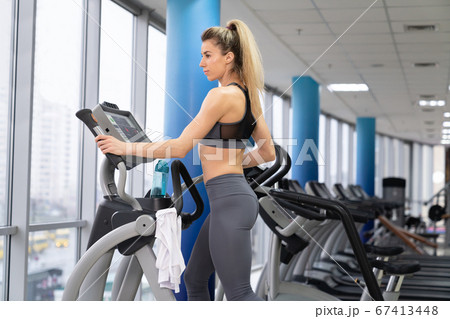 Young woman working out on orbi track at gym exercising 67413448