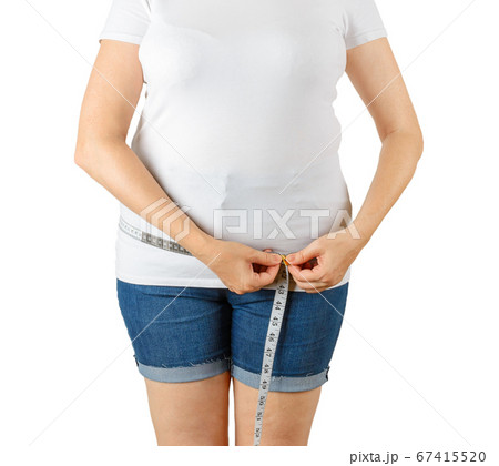 Caucasian mature adult woman begins to gain weight and measures her hips with a measuring tape. 67415520