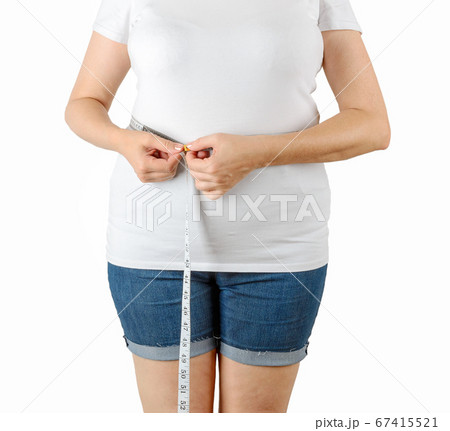 Caucasian mature adult woman begins to gain weight and measures her waist with a measuring tape. Caucasian mature adult woman begins to gain weight and measures her waist with a measuring tape. 67415521