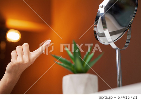 Woman puts on a contact lens for vision correction Woman puts on a contact lens for vision correction 67415721