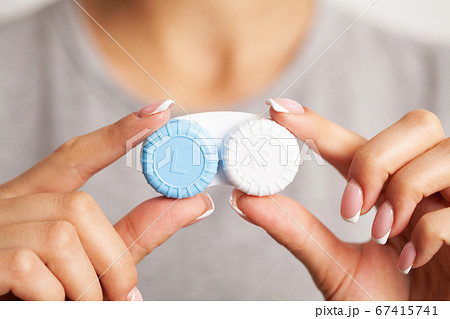 Woman holding a container with contact lenses for vision correction Woman holding a container with contact lenses for vision correction 67415741