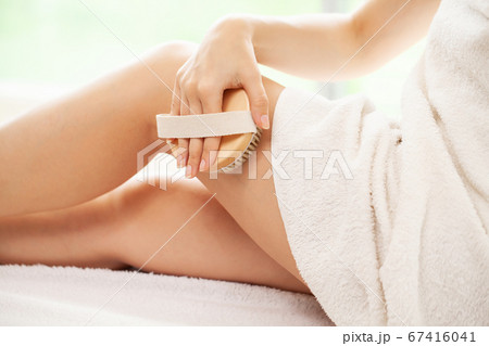 Cellulite treatment, woman arm holding dry brush to top of her leg. Cellulite treatment, woman arm holding dry brush to top of her leg. 67416041