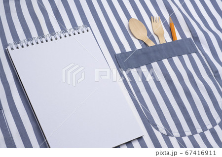ノートとエプロンのポケットに入れたカトラリーとエンピツ 67416911