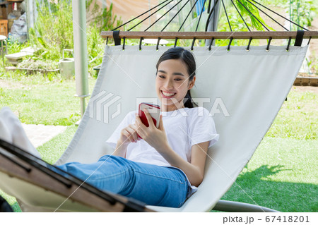 ハンモックでスマートフォンを操作する女性 ハンモックでスマートフォンを操作する女性 67418201