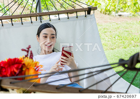 ハンモックでスマートフォンを操作する女性 67420697