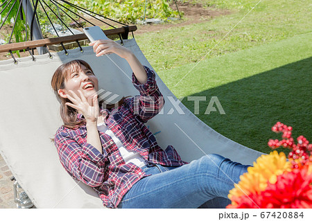ハンモックでスマートフォンを操作する女性 67420884