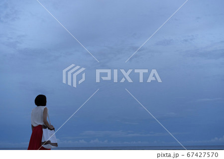 雲に覆われた大空を見つめるショートカットの女性 67427570