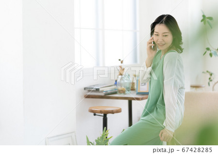 スマホで通話するミドル女性【リビング】 スマホで通話するミドル女性【リビング】 67428285