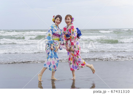 波打ち際で遊ぶ二人の浴衣の女性 67431310