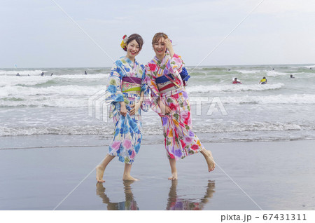 波打ち際で遊ぶ二人の浴衣の女性 67431311