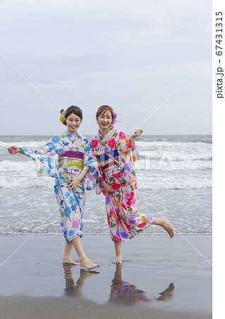 波打ち際で遊ぶ二人の浴衣の女性 67431315