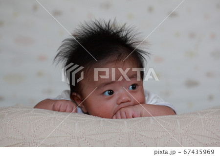 赤ちゃん首が座る前 うつ伏せの練習に飽きてお手ておしゃぶりの写真素材