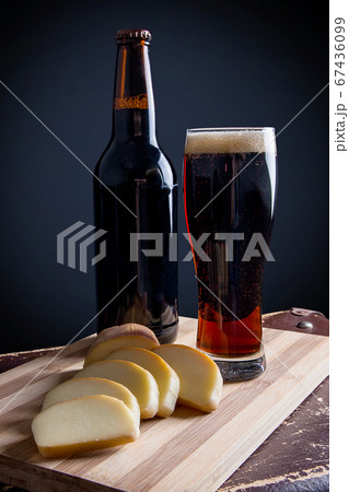Glass and Bottle of dark beer with smoked cheese 67436099