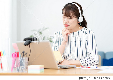 テレワーク 自宅で白いヘッドフォンをつけてウェブ会議をしているちょっと困った顔の若い女性 テレワーク 自宅で白いヘッドフォンをつけてウェブ会議をしているちょっと困った顔の若い女性 67437705