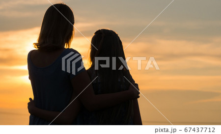 Silhouettes of mother and daughter at sunset 67437712