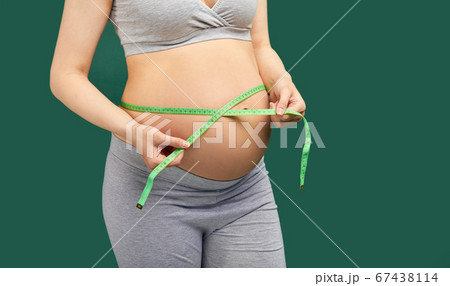 Pregnant woman measuring stomach with measuring tape Pregnant woman measuring stomach with measuring tape 67438114