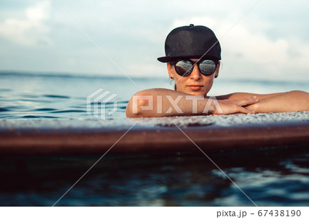 Beautiful girl posing sitting on a surfboard in Beautiful girl posing sitting on a surfboard in 67438190