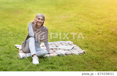 Positive muslim woman spending weekend at park 67439631