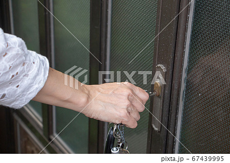玄関の引き戸の鍵を閉める女性 67439995