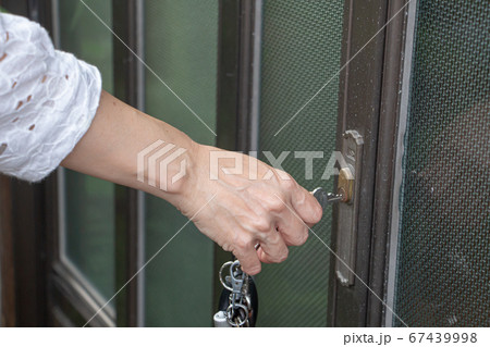 玄関の引き戸の鍵を閉める女性の写真素材