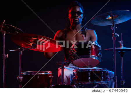 Attractive african man drummer enjoying playing drums over dark background 67440546