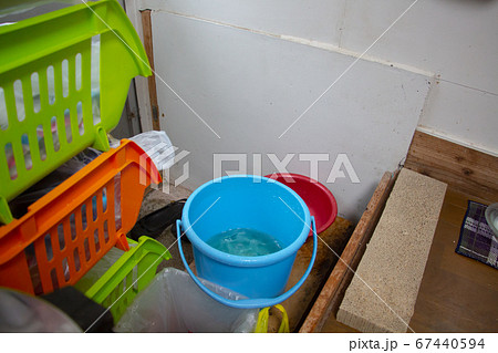 雨漏りしている勝手口に置いているバケツと洗面器　雨漏り被害の日本家屋 67440594