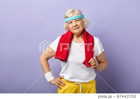 Elderly sportswoman with headband and red towel on neck, looking at camera Elderly sportswoman with headband and red towel on neck, looking at camera 67442702