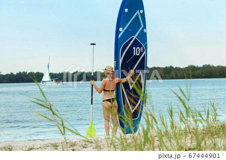 Young attractive woman standing next to paddle board, SUP. Active life, sport, leisure activity concept 67444901