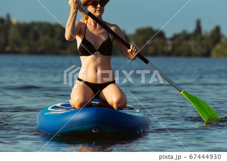 Young attractive woman sitting on paddle board, SUP. Active life, sport, leisure activity concept 67444930
