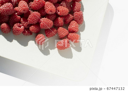 Fresh raspberries on square caremic plate. Close up photo of sweet forest berries with bright sunlight. Fresh raspberries on square caremic plate. Close up photo of sweet forest berries with bright sunlight. 67447132