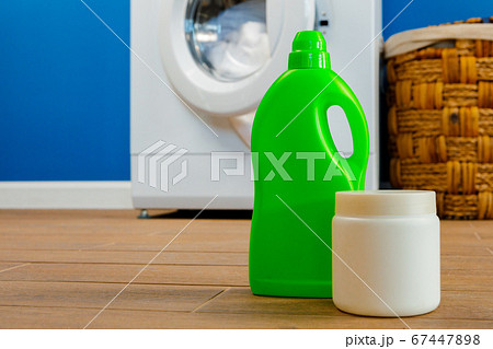 Washing machine with laundry on blue wall background Washing machine with laundry on blue wall background 67447898