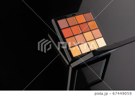 Professional pallet of eyeshadow. Multicoloured crumbled eye shadows on black table. 67449059