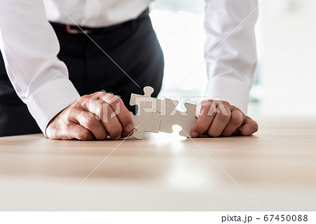 Businessman connecting two matching puzzle pieces Businessman connecting two matching puzzle pieces 67450088