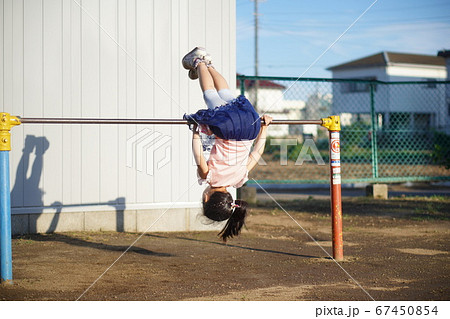 鉄棒で逆上がりをする女の子の写真素材