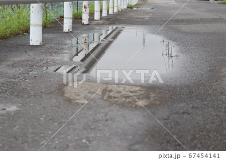 ガードレールと水たまりが出来た道路 ガードレールと水たまりが出来た道路 67454141