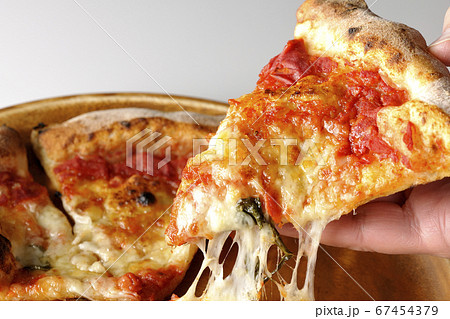 マルゲリータを食べようとピザを取る手も入ったカット 67454379