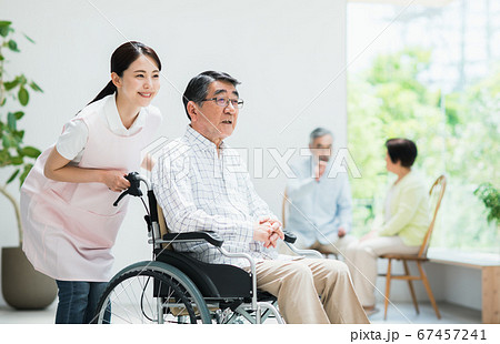 車いすの男性と介護の若い女性 67457241
