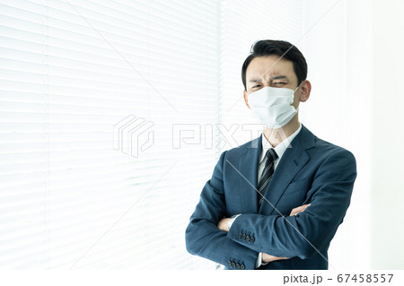 深刻そうに考えるマスクを着けた男性　感染症対策 67458557