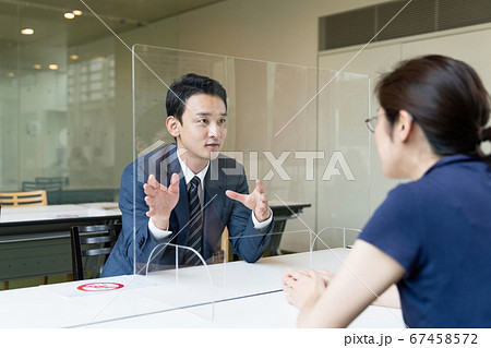 アクリルパーティション越しに話すビジネスマン　感染対策　ソーシャルディスタンス 67458572