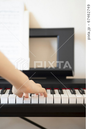 楽譜を見ながら電子ピアノを弾く女性の上半身の写真素材