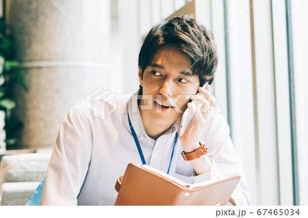 手帳を持って電話をする若い男性 手帳を持って電話をする若い男性 67465034