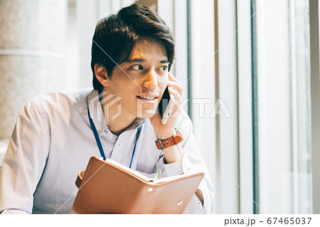 手帳を持って電話をする若い男性 手帳を持って電話をする若い男性 67465037